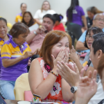 Happy crowd reacting during Allan Reyes community event indoors.